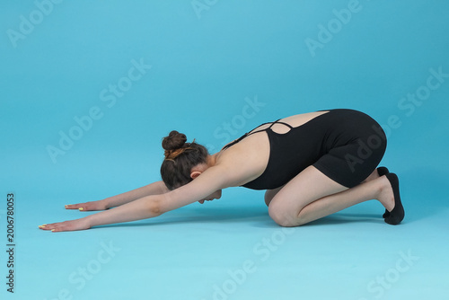 Schilderij op canvas Young woman practicing child pose yoga stretch in studio