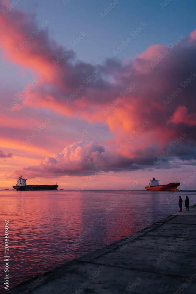 Fototapeta premium Two ships near pier with people watching colorful sunset