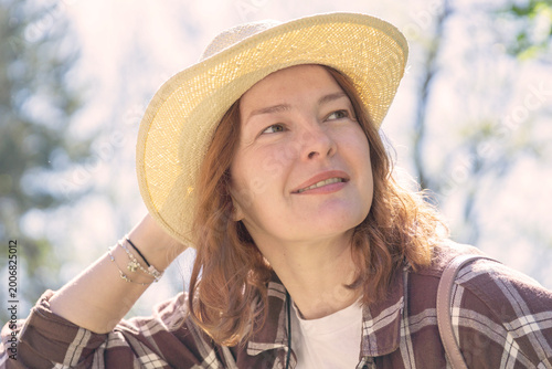 woman relaxing park summer hat straw accessory portrait of female smiling with closed eyes enjoying sun gazing away in green forest outdoor garden atmosphere concept of lifestyle, travel, wellness