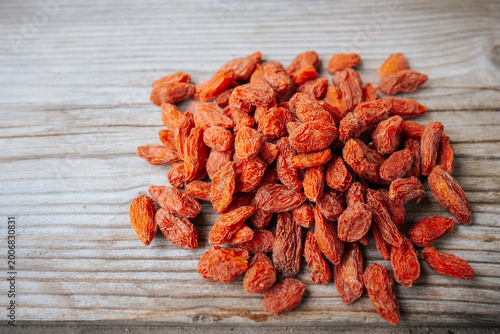 Foto Dried red goji berries scattered on a rustic wooden surface with shallow focus, highlighting the wrinkled texture and warm natural color