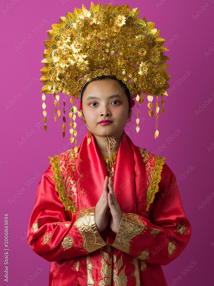 Naklejka premium Young Indonesian Asian Girl Wearing Ornate Gold Headdress and Traditional Red Chinese Costume Portrait