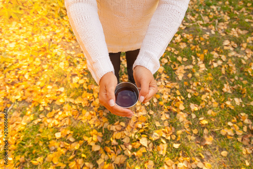 Tableau sur toile Girl holding a hot drink on a background of autumn foliage