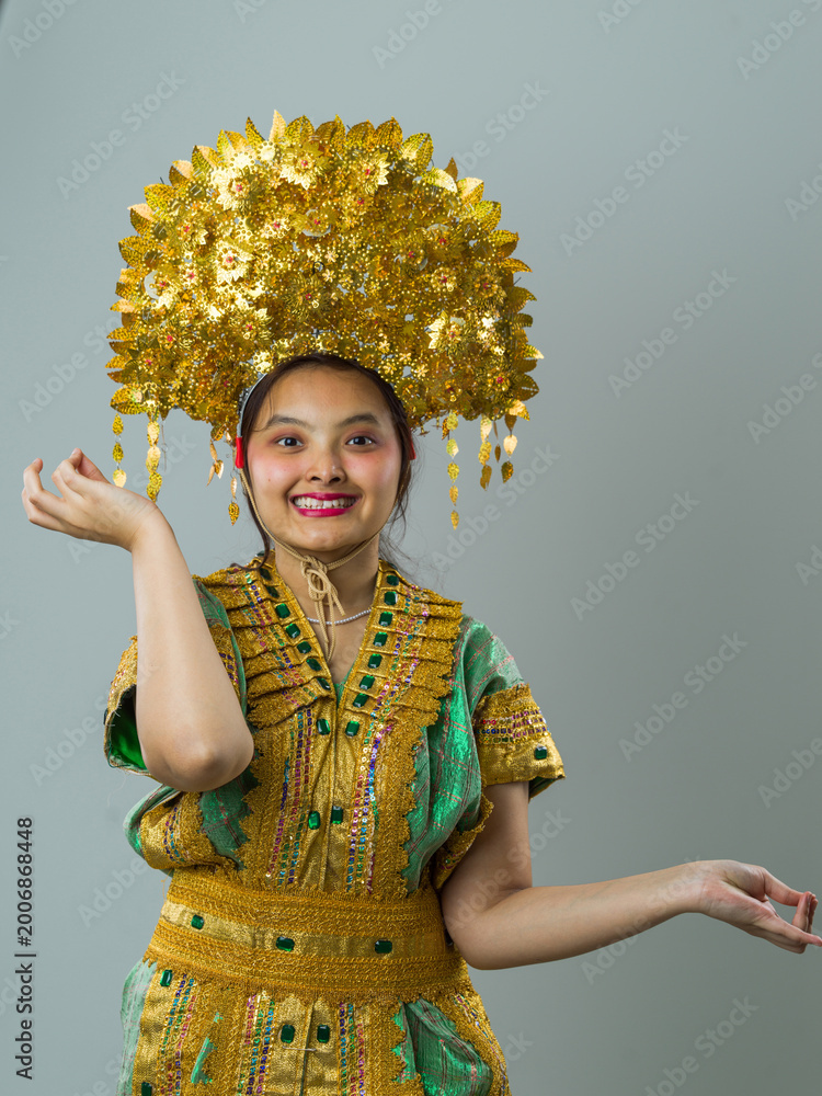 Fototapeta premium Young Indonesian Asian Woman Wearing Gold Headdress and Traditional Costume Smiling in Cultural Portrait