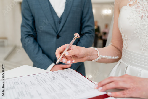 Bride signing wedding certificate, couple during marriage registration ceremony