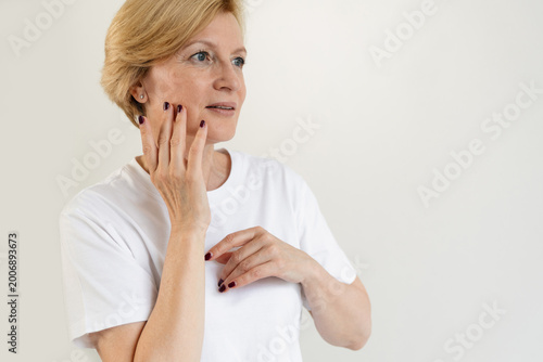 Mature woman caring for her skin in a simple space