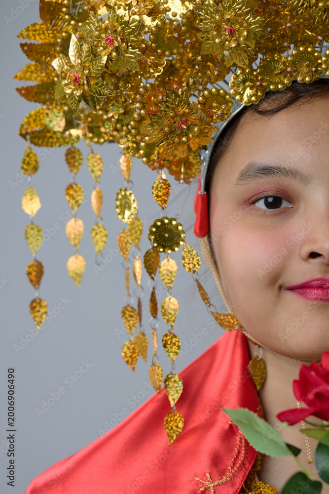 Obraz premium Portrait Of Young Indonesian Asian Woman Wearing Ornate Gold Traditional Headdress And Red Costume For Celebration