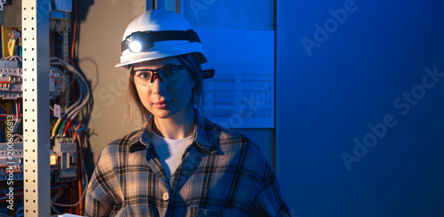 Electrical engineer standing near switchboard holding system blueprint. Professional portrait.