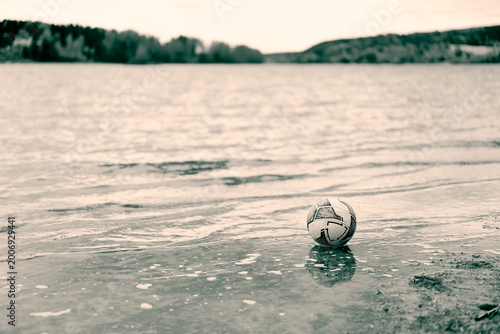Abandoned Soccer Ball on the Shore of a Nordic River in Muted Tones