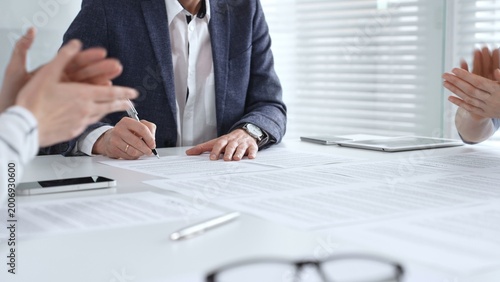 Photography Business professional hand holding a pen, signing a document on a white desk dur
