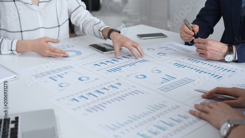Business team in a conference room reviewing financial reports, charts and graphs across the table, collaborating on strategy, investment planning and growth initiatives