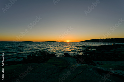 Sunset over Nordic Rocky Coastline with Calm Sea and Golden Horizon