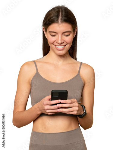 Portrait of fit woman standing with phone watching online workout tutorial