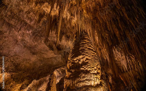 Photography Golden glow illuminates ancient limestone stalactites inside the cave