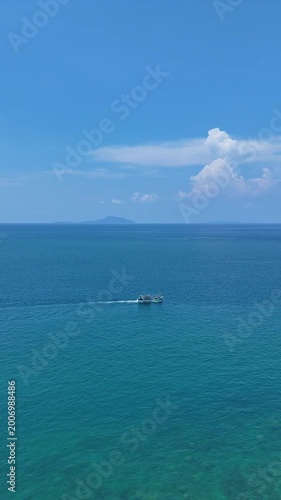 Sailboat Glides Peacefully on Vast Blue Sea with Distant Island and Hills Under Clear Sky, Evoking Tranquility on Ocean Horizon	