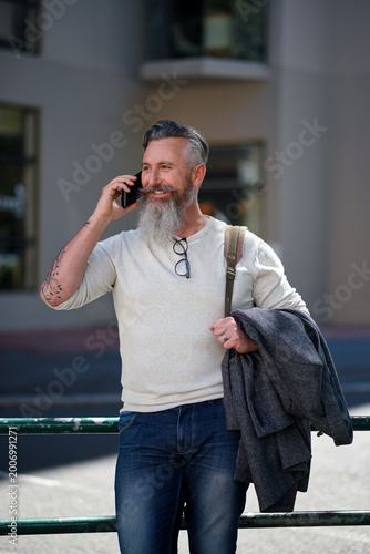 Mature, man and phone call in city for communication, happy chat or catchup with contact on trip. Male person, technology and smile with conversation on walk in street, network and travel in town