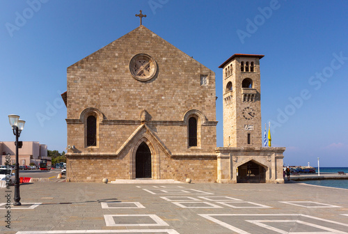Stone church with clock tower on Mandraki harbor square in Rhodes Greece