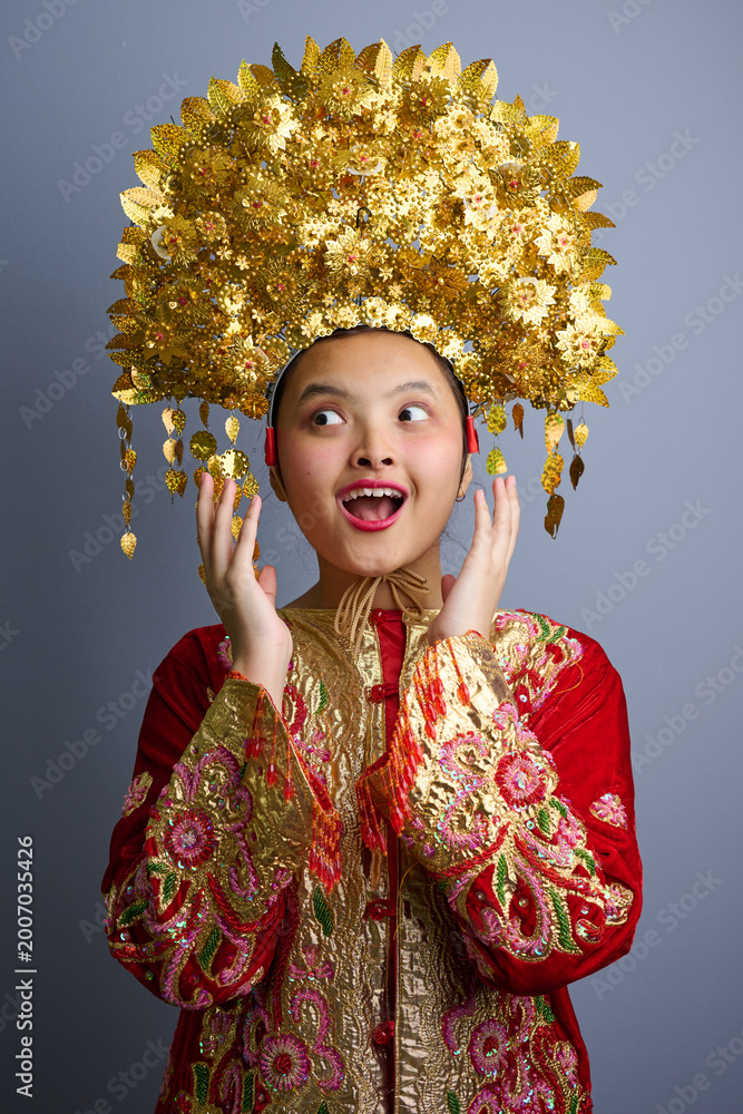 Obraz premium Young Indonesian Asian Girl Wearing Ornate Gold Chinese Headdress And Embroidered Red Traditional Costume