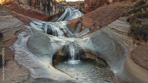 Multi tiered waterfall cascading down sculpted canyon walls into a pool