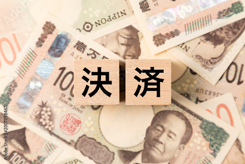 「決済」と書かれたブロックとたくさんの一万円札