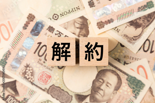 「解約」と書かれたブロックとたくさんの一万円札