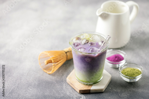 Ube tea is poured in iced matcha milk. Healthy vegan drink Ube Matcha Latte