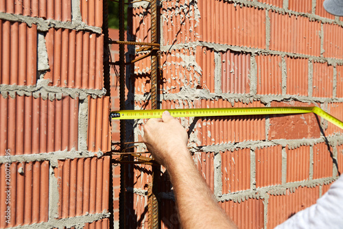 A construction worker is measuring a brick wall at a building site