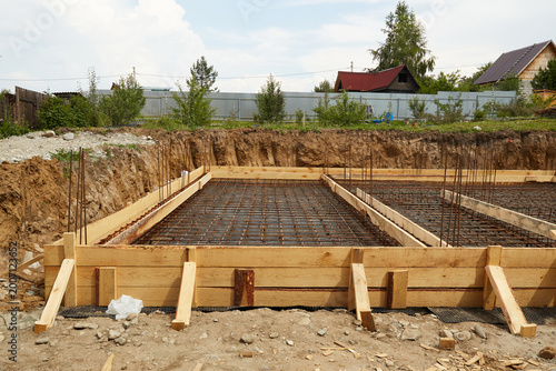 Steel reinforcement is placed in wooden molds and formwork on a construction site