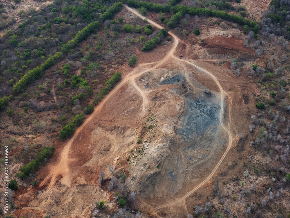 Fototapeta premium Dirt road leads to excavated area in forested region