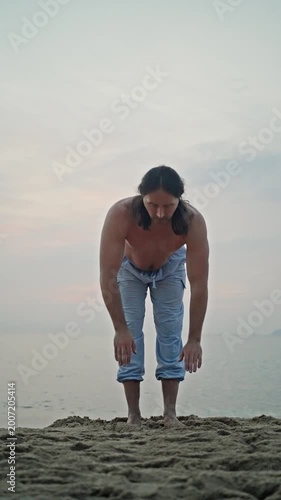 Man Performing Forward Bend On Sandy Shore At Sunrise, Barefoot And Focused, Calm Ocean Backdrop With Soft Morning Light, Wellness And Mindfulness Practice In Natural Coastal Setting