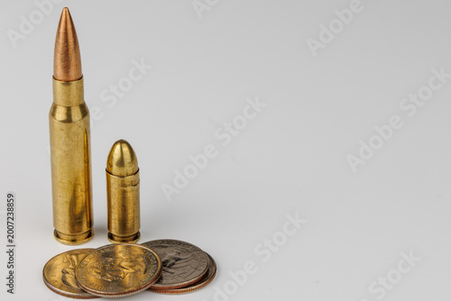 Detailed view of a rifle ammunition round and American currency on a neutral background. Concept of military spending, safety and weapon prices now.