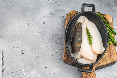 Schilderij op canvas Fresh dab flatfish fillets with herbs and garlic in cast iron pan, raw seafood i