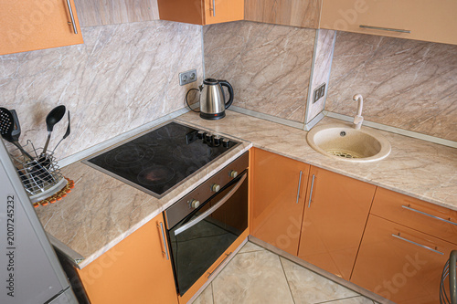 Photos compact kitchen with orange cabinets, marble-patterned countertops and backsplas