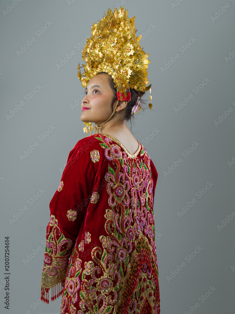 Fototapeta premium Young Indonesian Asian Woman in Red Embroidered Dress With Ornate Gold Headdress Wearing Traditional Cultural Costume
