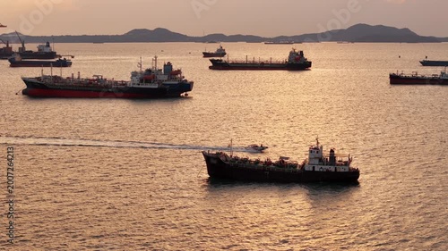 fast patrol boat with LPG gas and oil tanker ships anchored in the ocean, with a fast patrol boat in the foreground. Global energy transport, war energy crisis, and Strait of Hormuz blockade concept.	