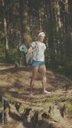 Forest hiking journey, Female traveler carefully crosses roots on sunny trail engaging in outdoor adventure