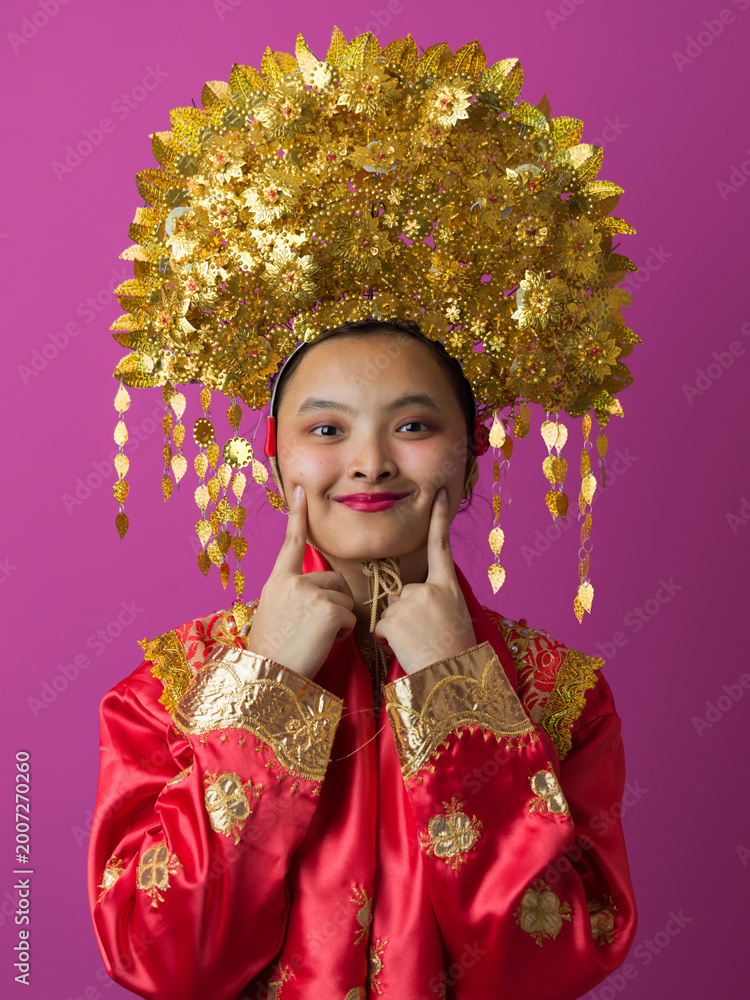 Fototapeta premium Portrait of Smiling Indonesian Asian Woman in Traditional Gold Headdress and Red Festive Costume for Celebration
