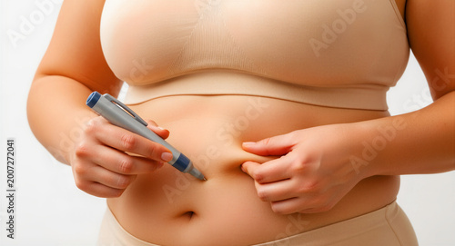 Woman injecting medication into her abdomen with a pen injector. Patient performing self-care for diabetes or weight loss treatment. Medical therapy concept for pharma ads and healthcare blogs.