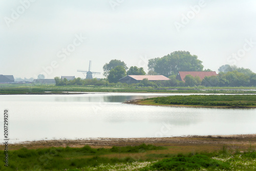 National Park in Holland. Landscape in spring with fog. Windmill an farm. Netherlands, Zeeland, Oosterschelde.