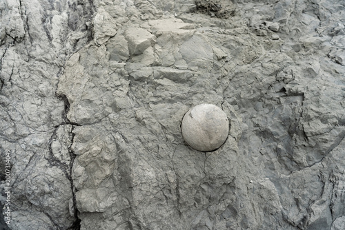 Cannonball sized round rock protruding from cliff face