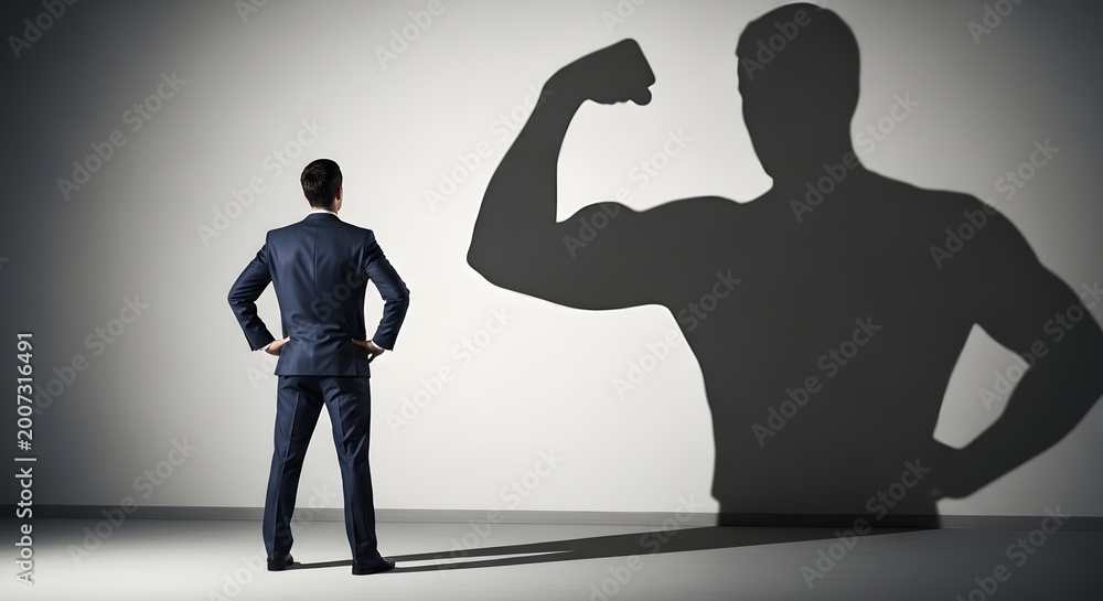 Naklejka premium Man facing his strong shadow flexing muscles