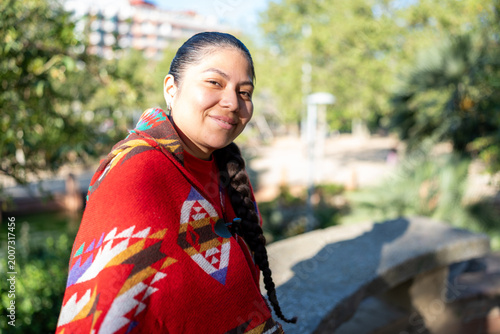 Peruvian indigenous woman smiling, wearing a traditional poncho in a sunny park