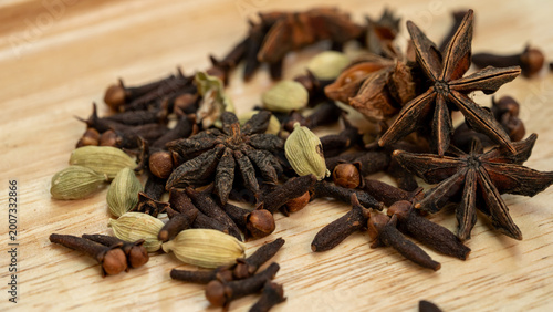Aromatic Indian Spices Including Star Anise Cinnamon and Cardamom Dropping on Wood Surface