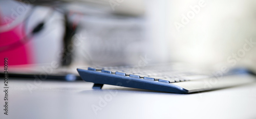 Macro side view of a dark computer keyboard resting on a corporate workspace table. Modern IT equipment background illustrating digital communication and remote work. Photo