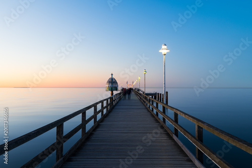Seebrücke Zinnowitz bei Sonnenuntergang mit Holzsteg, Lampen und ruhiger Ostsee unter klarem Himmel in der Abenddämmerung