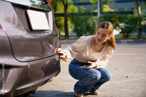Fotografia Woman inspecting damaged car bumper after minor accident