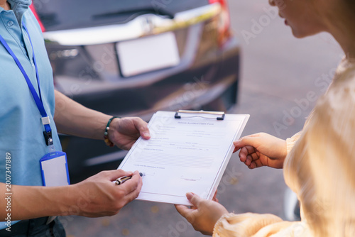 Close up of woman signing car insurance claim form with agent