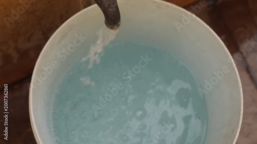 Raw 4K footage of water filling a bucket from a pipe, showing daily water usage, simple rural lifestyle, and basic resource collection in an Indian village.