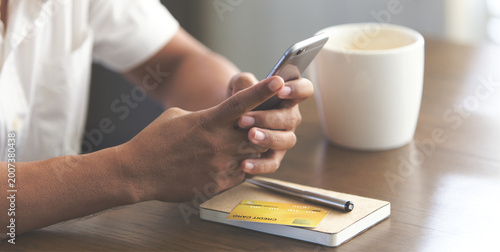 Person using smartphone with credit card on a wooden table, representing online payment, digital banking, and modern financial lifestyle