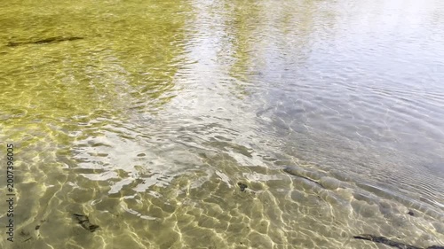 Clear water flows gently over the sandy bottom