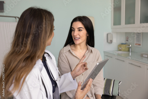 Obraz na plátne Doctor showing medical information, scan results on tablet to patient, explainin